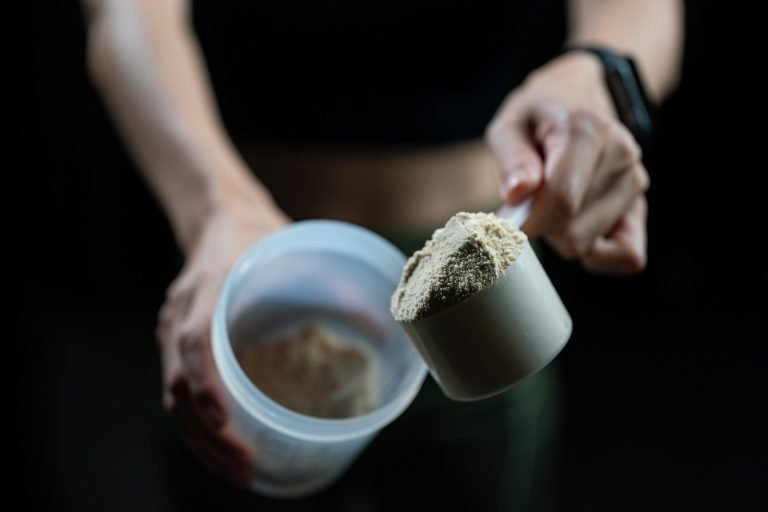 Dosador de whey protein isolado sendo colocado na coqueteleira