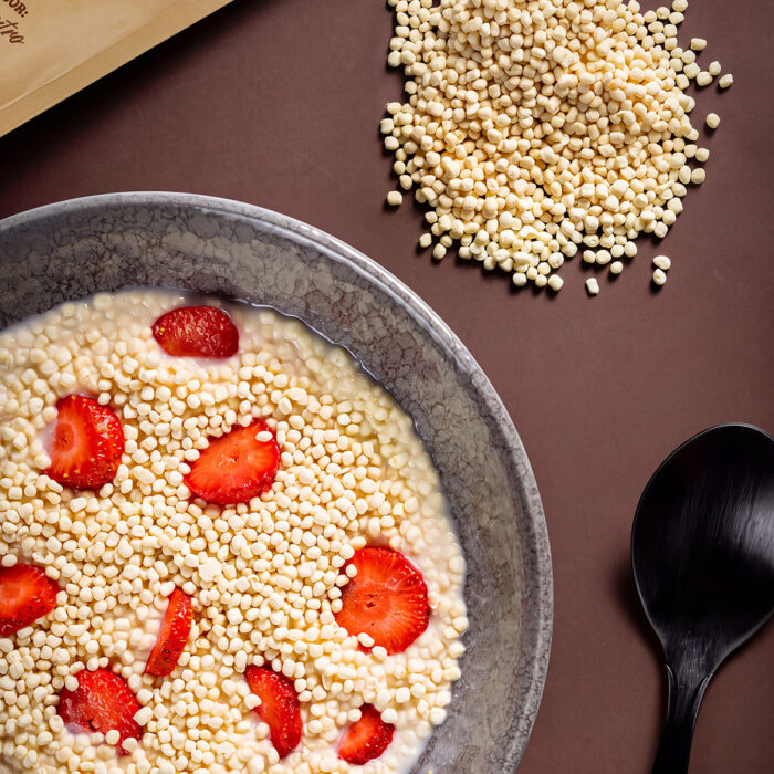 Tigela com Crispy Wise Whey e morangos fatiados sobre fundo marrom