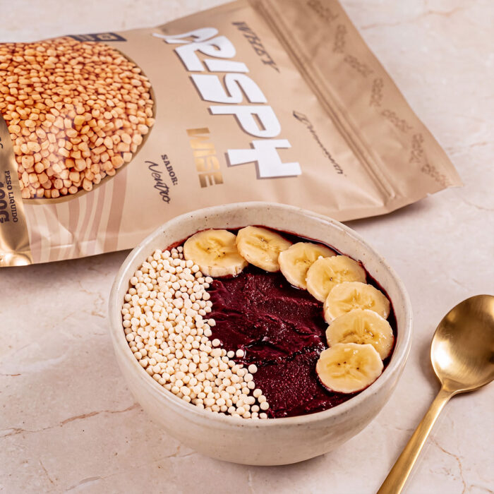 Tigela de açaí com banana e Crispy Wise Whey, ao fundo o pacote de 400 g